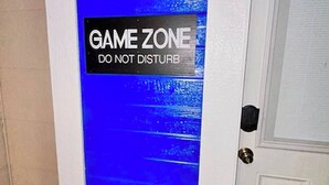 Una porta con una sfumatura blu e un cartello con la scritta 'GAME ZONE DO NOT DISTURB'.