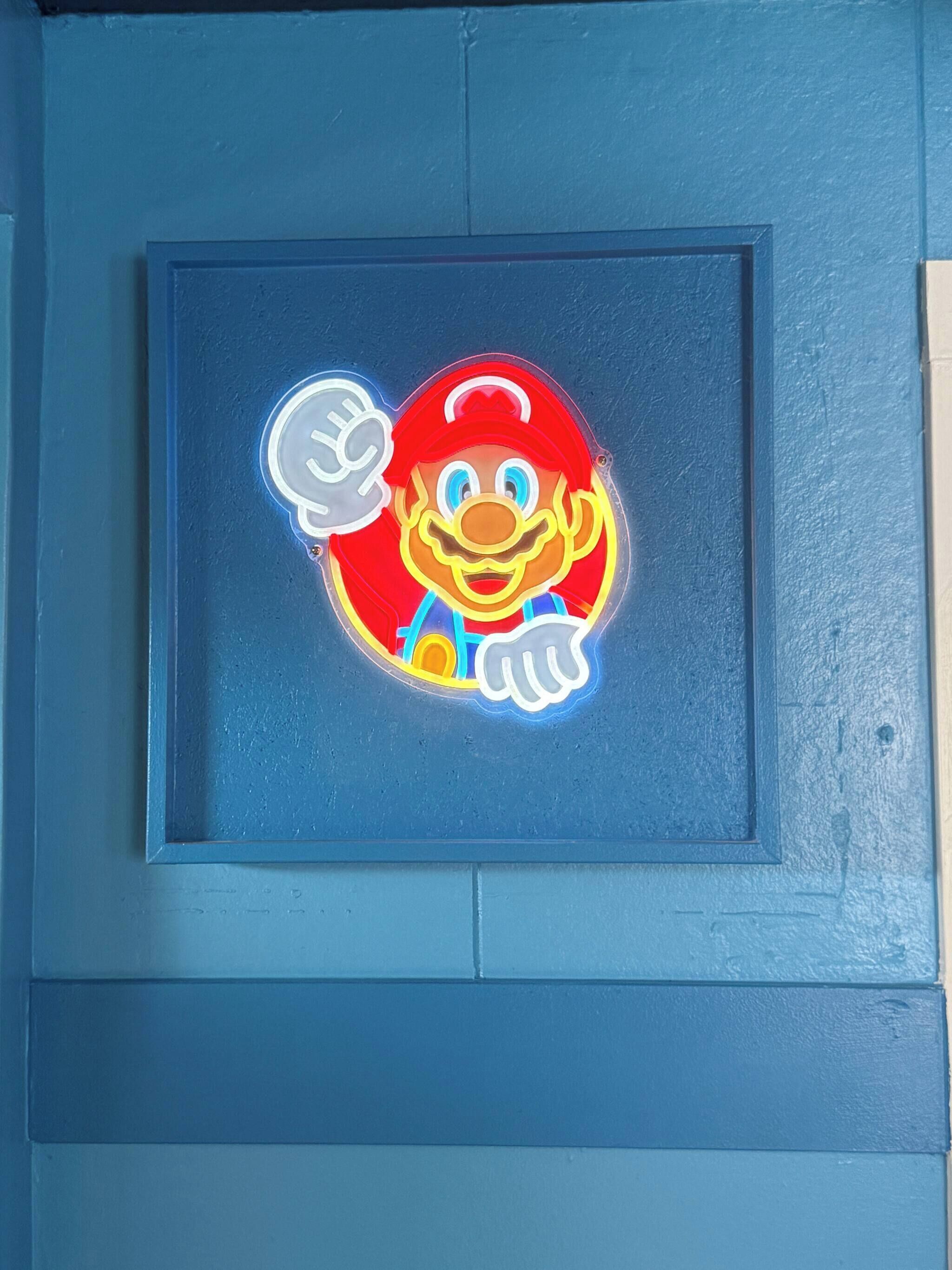 A framed Mario character with a thumbs-up sign.