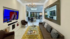 Una sala de estar moderna con un televisor de pantalla plana, un sofá, una mesa de centro y un espejo grande.