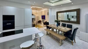 Una cocina moderna con comedor, que incluye un horno empotrado, una mesa de comedor con sillas y un espejo grande sobre la mesa.