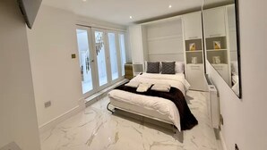 Un dormitorio moderno con una cama grande, un armario con espejo y vistas al exterior mediante una puerta corredera.