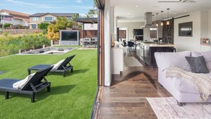 Une maison moderne dotée d’un vaste espace de vie, d’une cuisine et d’un jardin avec une piscine et du mobilier d’extérieur.