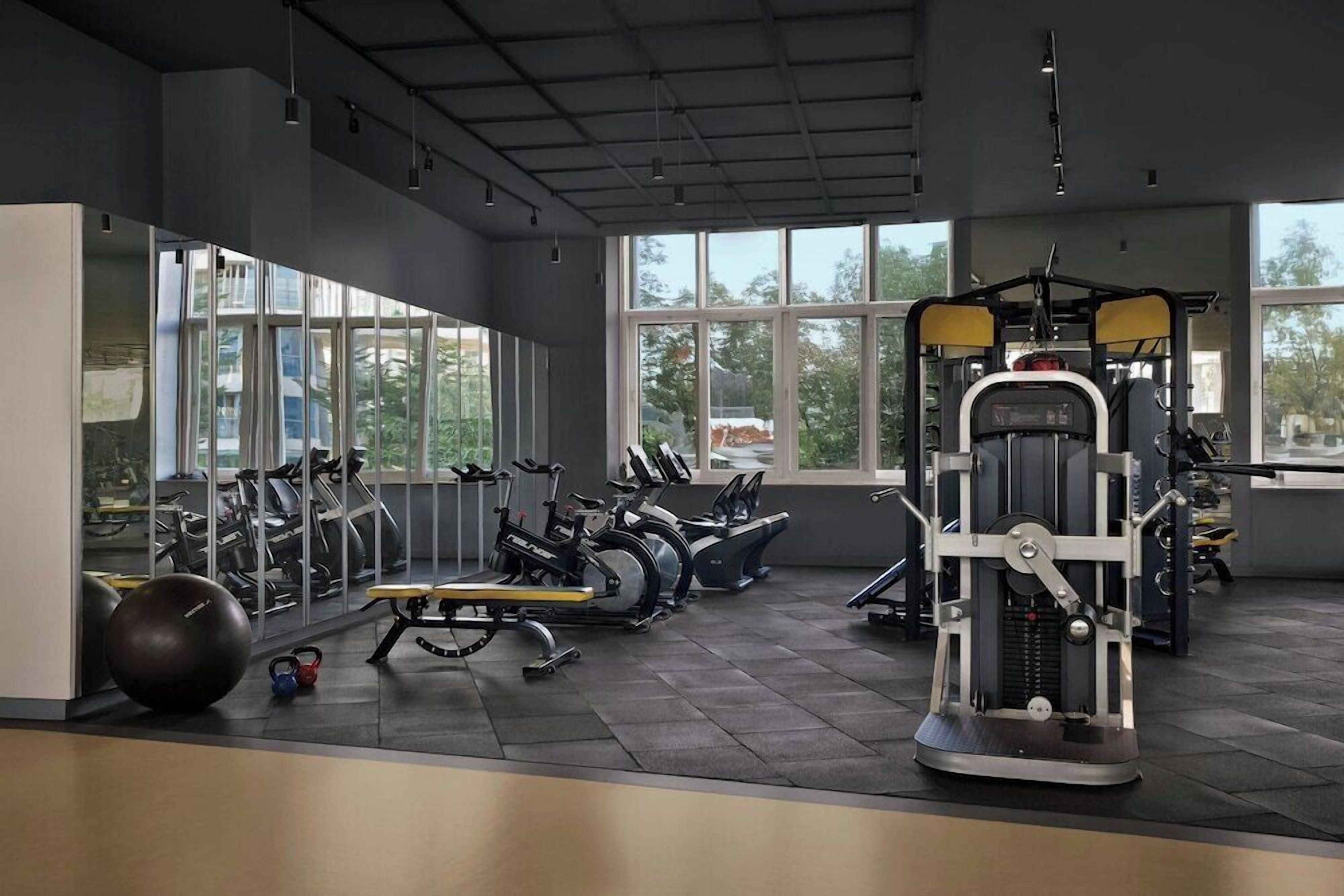 A gym with exercise equipment, large windows, and a view of the outdoors.