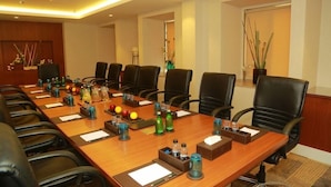 A conference room with a long table, multiple chairs, and various amenities like water bottles and notepads. - Amanora the Fern Hotels And Club (Pune)