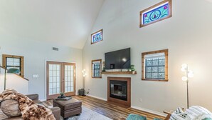 A spacious living room with a fireplace, a television, and a large window with stained glass. - River Access, Starlink, Fire Pit, W/D, Peaceful Discount, Peaceful (Mcgregor)