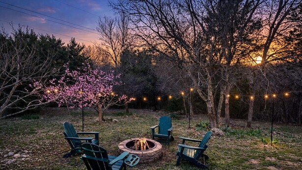 A backyard with a fire pit, green Adirondack chairs, and string lights. - River Access, Starlink, Fire Pit, W/D, Peaceful Discount, Peaceful (Mcgregor)