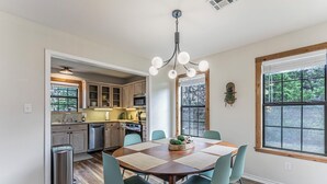 A kitchen with wooden cabinets, a dining table with chairs, and a chandelier. - River Access, Starlink, Fire Pit, W/D, Peaceful Discount, Peaceful (Mcgregor)