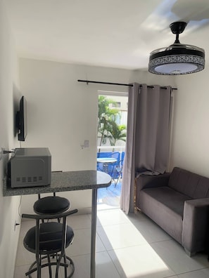 Um espaço de estar compacto com cozinha compacta, um sofá, uma mesa de jantar e um ventilador de teto.