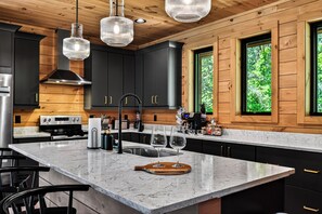 Een moderne keuken met een marmeren eiland, zwarte kastjes en houten details.