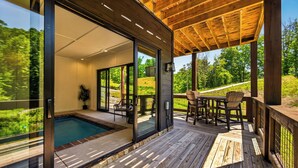 Eine moderne Außenterrasse mit Pool, Glasfenstern und einer Holzpergola.