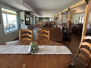 A spacious living area with a dining table set for two, wooden chairs, and a sofa.