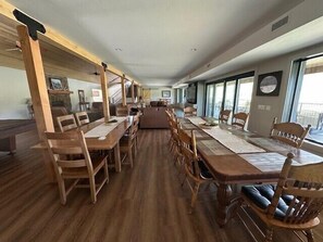 A spacious dining area with wooden tables and chairs, large windows, and a view of the outdoors.