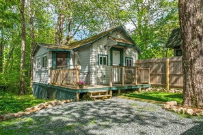 Eine Holzhütte mit Veranda, umgeben von Bäumen und einem Holzzaun.