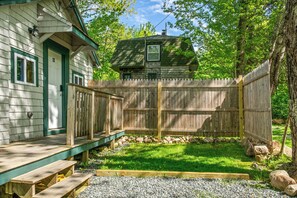 Ein Holzhaus mit grüner Tür, einer Terrasse und einem eingezäunten Garten.
