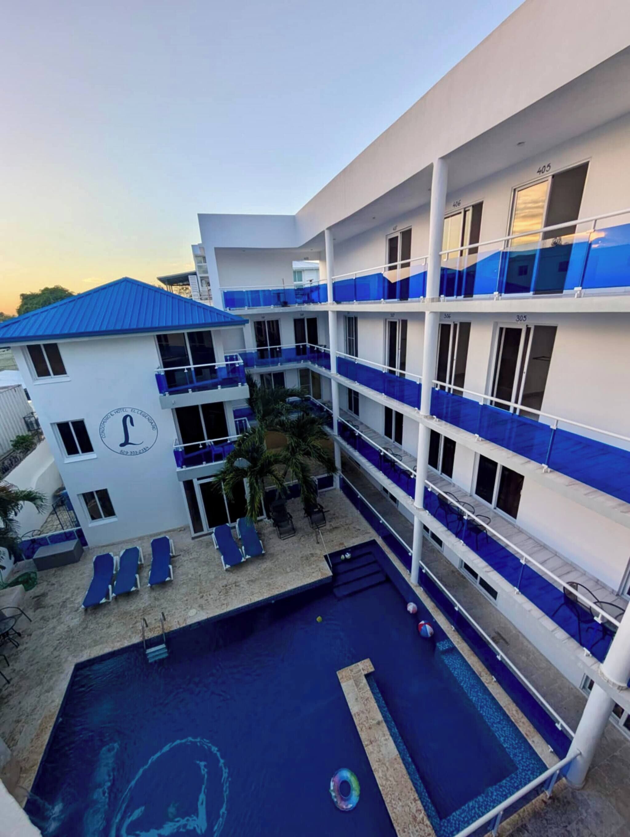 A multi-story hotel with a pool area, including lounge chairs and a small pool.