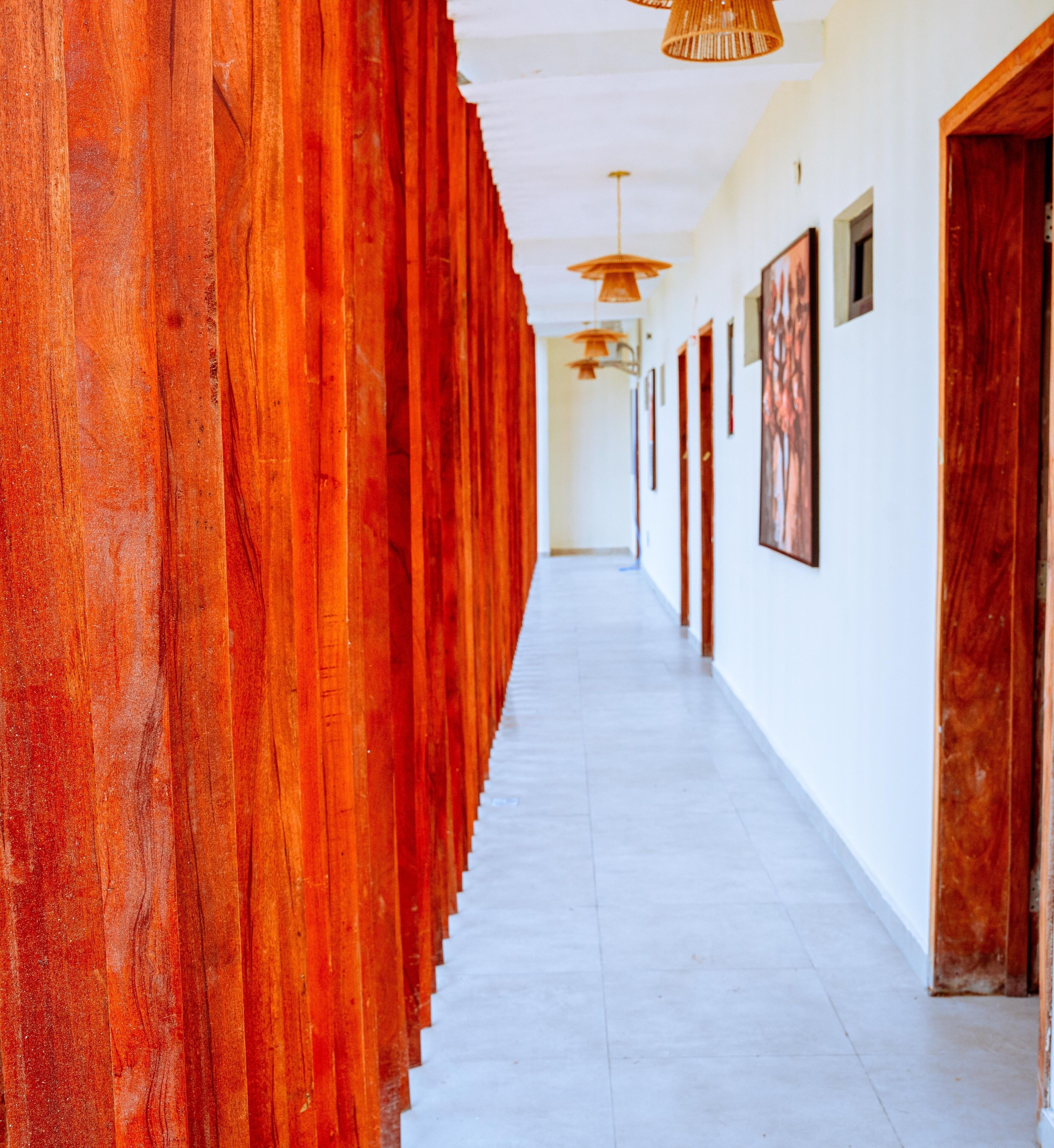 Un largo pasillo con una pared roja en un lado y paredes blancas en el otro, que conduce a una puerta al final.