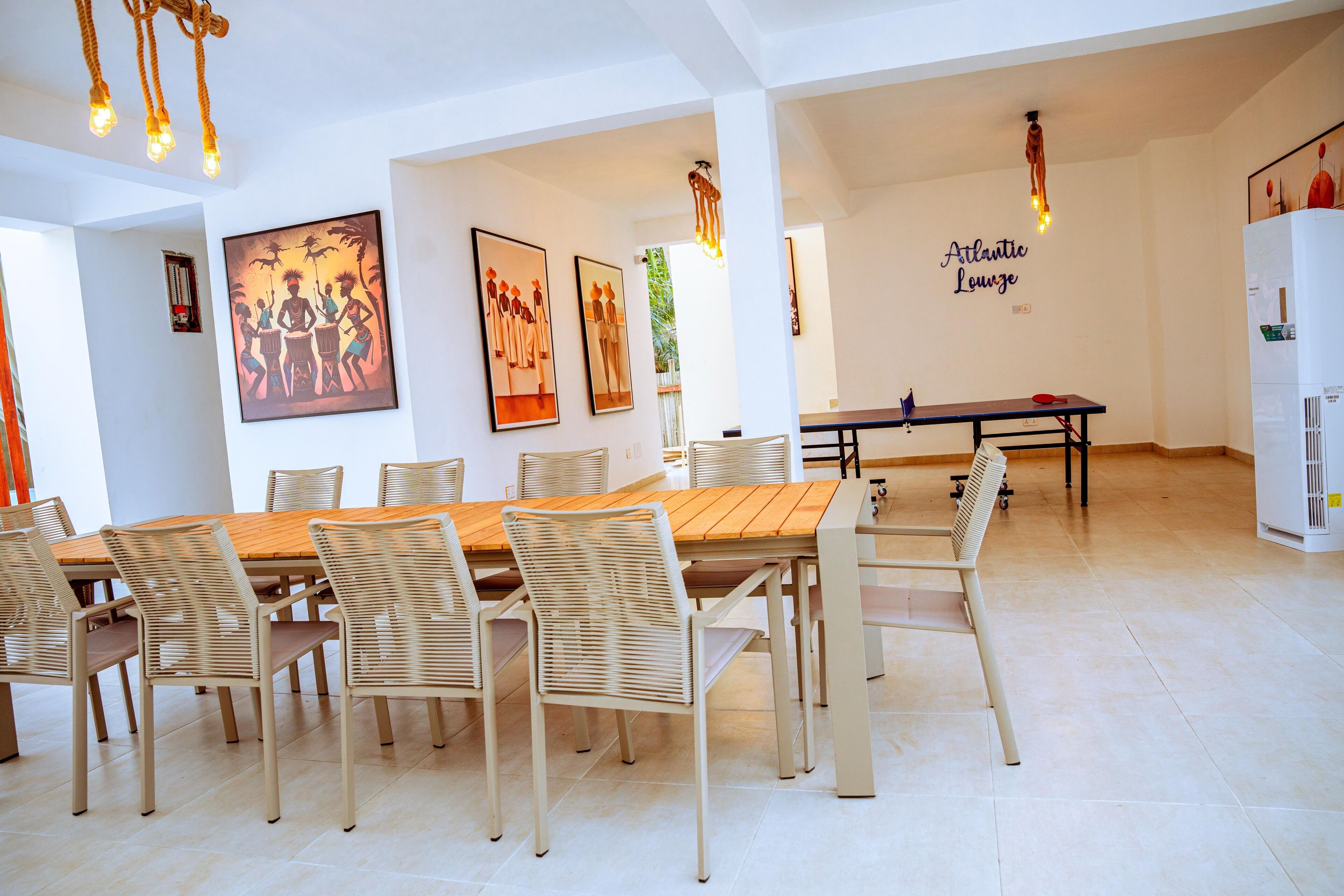 Un comedor con una mesa de madera y sillas blancas, obras de arte enmarcadas en las paredes y un letrero que dice "Atlantic Lounge".