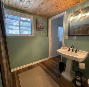 A bathroom with a wooden ceiling, a window, a sink, and a mirror. - Secluded A Frame Cabin, On 27 Acres by the Lake (Maynooth)