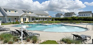 Une piscine avec des chaises longues et un espace patio couvert.