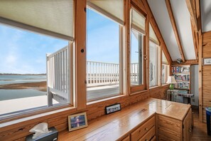 A wooden cabin with large windows overlooking a beach and water.