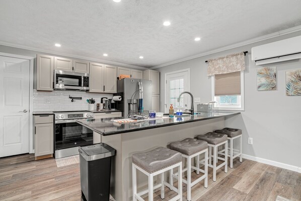 A modern kitchen with white cabinets, stainless steel appliances, and a central island with bar stools.