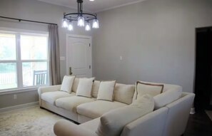 Un salon avec un canapé beige, un lustre et une vue sur un balcon.