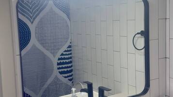 A bathroom with a white sink, a large mirror, and three wall-mounted lights.