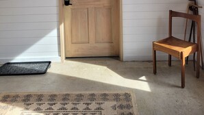 A wooden door with the number 2, a black metal coat rack, a framed picture, and a wooden chair. - The Cork Cottages Unit 2, Arcade Table, 1K/1Q 2 Bath, New and Modern (Geneva)