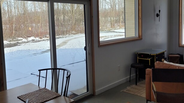 A spacious room with large windows, a ceiling fan, and a dining area with a table and chairs. - The Cork Cottages Unit 2, Arcade Table, 1K/1Q 2 Bath, New and Modern (Geneva)