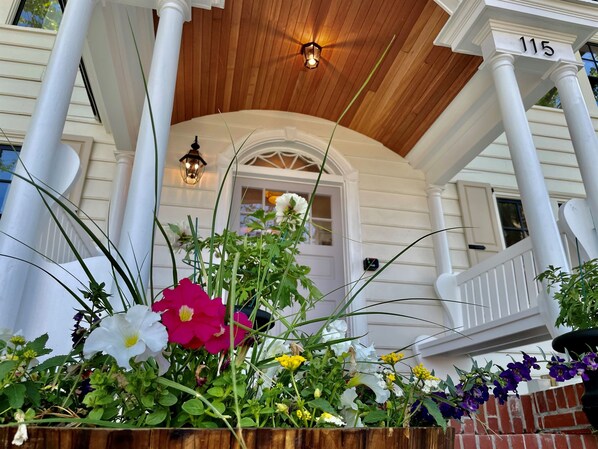 A porch with a wooden ceiling, white columns, and a brick wall. - Buttonwood Boutique Hotel Suite #3, Beach & Town (West Cape May)