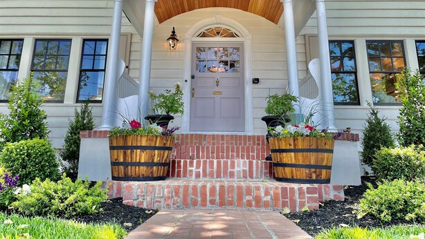 A two-story house with a front porch, a wooden door, and a number '115' above the door.
