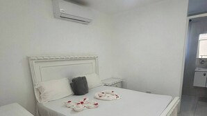 Una camera d'albergo ordinata con un letto, un comodino e un condizionatore.
