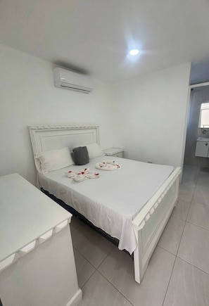A neatly arranged hotel room with a bed, bedside table, and an air conditioning unit. - Condo Neuf, Balcon en Plein Coeur de Sosua, 205 (Sosúa)