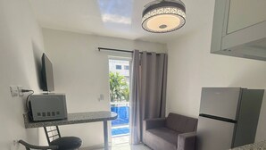 Una cucina compatta con piano cottura a gas, un piccolo tavolo da pranzo con sedie, un divano e un lampadario.