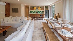 Una sala de estar moderna con un sofá, una mesa de comedor para seis personas y una cocina al fondo.