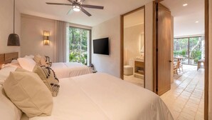 Une chambre d’hôtel avec deux lits, un ventilateur de plafond, une télévision et un balcon équipé d’une table et de chaises.