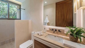 Une salle de bain moderne avec une grande fenêtre, un lavabo avec un miroir, un porte-serviettes et une plante.