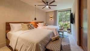 Une chambre d’hôtel avec deux lits, un ventilateur de plafond, un téléviseur fixé au mur et une vue sur l’extérieur.