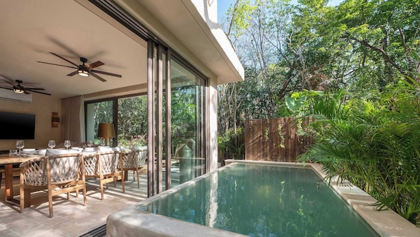 Un área de piscina al aire libre con zona de comedor y ventiladores de techo.