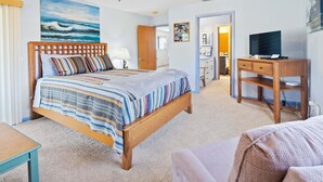 Een slaapkamer met een bed, een bureau, een televisie en een deur naar een badkamer.