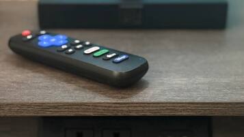 Kauko-ohjain puupinnalla, taustalla musta elektroninen laite.