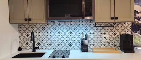 A kitchen with beige cabinets, a stainless steel microwave, a sink, and a dishwasher.