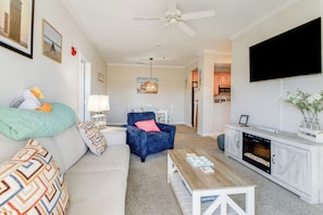 A modern living room with a sofa, a blue armchair, a wooden coffee table, and a TV mounted on the wall. - Dog-Friendly Rehoboth Beach Escape • 4 Mi to Beach (Rehoboth Beach)
