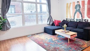 En moderne stue med et stort vindue, en sofa, et sofabord og et farverigt tæppe.