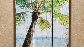 A painting of a palm tree with a beach and ocean in the background.