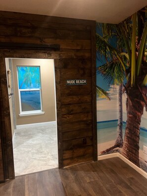 A wooden door with a sign reading "NUDE BEACH" and a mural of a palm tree. - Tropical Spa Studio, Jacuzzi, Kitchen, Sparks (Sparks)
