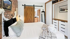 Un dormitorio con una cama grande, una puerta de madera, un aparador y un espejo.