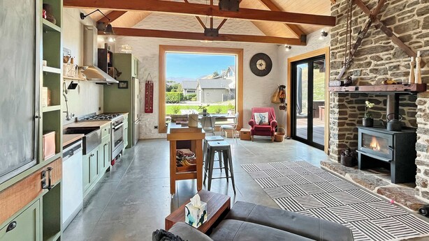 Un salón amplio con cocina, chimenea de piedra y vistas al exterior.
