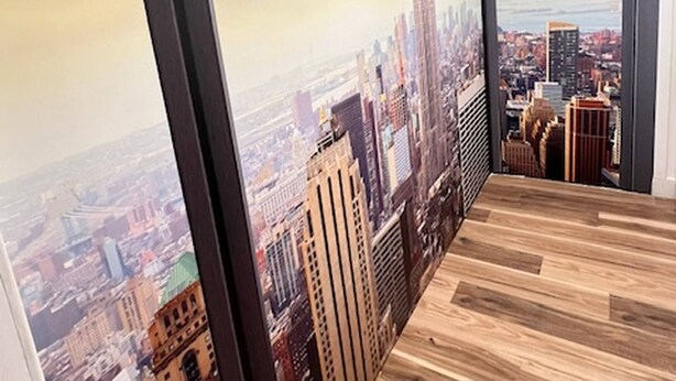 A room with a large cityscape mural on the wall, a wooden floor, and a black-framed window. - Deco Studio Retreat With Fireplace, Wifi, Queen Bed (Reno)