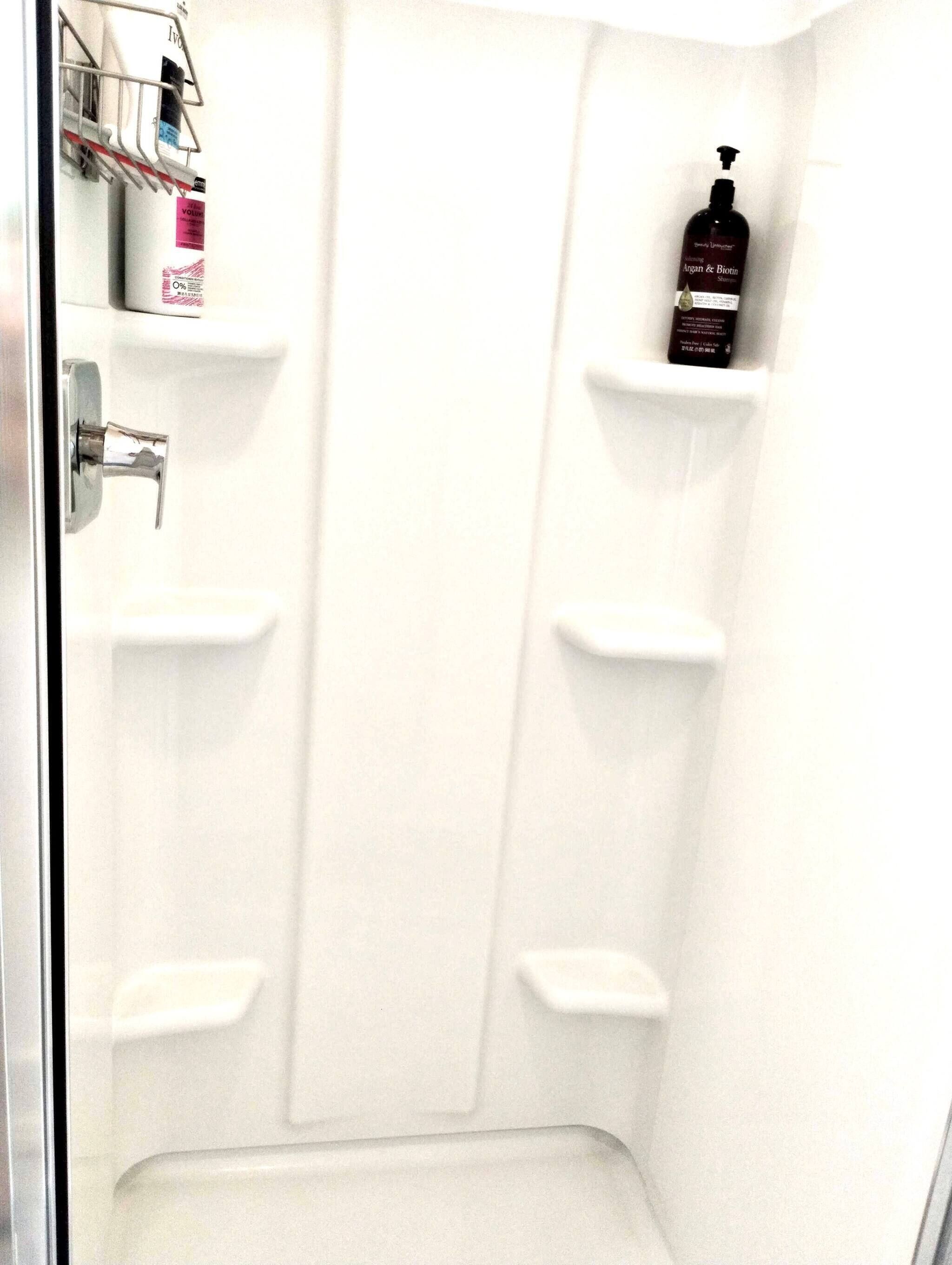 A shower with multiple shelves for toiletries.
